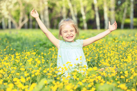 Happy little girl on spring blooming meadowの写真素材