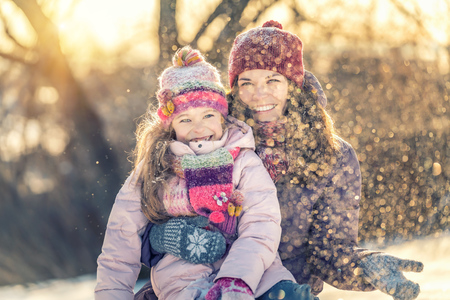 Little girl and her mother playing outdoors at sunny winter dayの写真素材