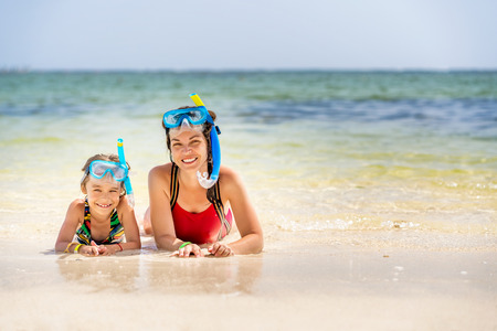 Young mother and little daughter in snorkeling masks enjoing the beach in Dominican Republicの写真素材