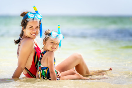 Young mother and little daughter in snorkeling masks enjoing the beach in Dominican Republicの写真素材