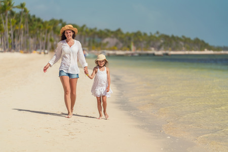Young mother and little daughter walking on the beach in Dominican Republicの写真素材