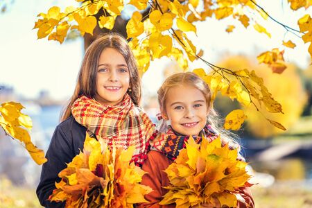 Two cute smiling 8 years old girls posing together in a park on a sunny autumn day. Friendship concept.の写真素材