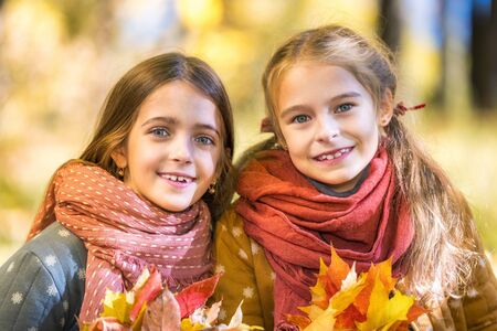 Two cute smiling 8 years old girls posing together in a park on a sunny autumn day. Friendship concept.の写真素材
