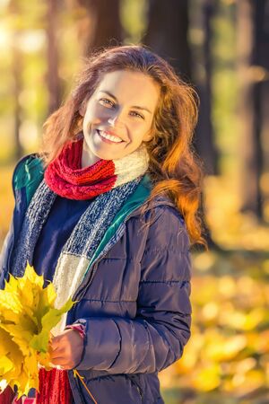 Young beautiful woman enjoys sunny autumn day in the parkの写真素材