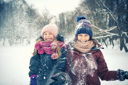 Little girl and her mother playing outdoors at winter day. Active winter holydays concept.の写真素材