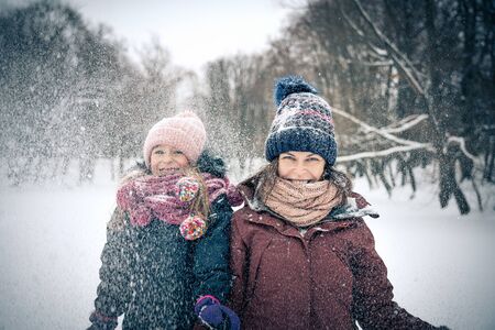 Little girl and her mother playing outdoors at winter day. Active winter holydays concept.の写真素材
