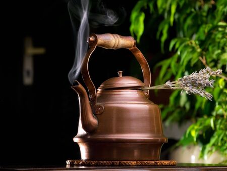 Hot lavender tea in a copper teapot on the table.の写真素材
