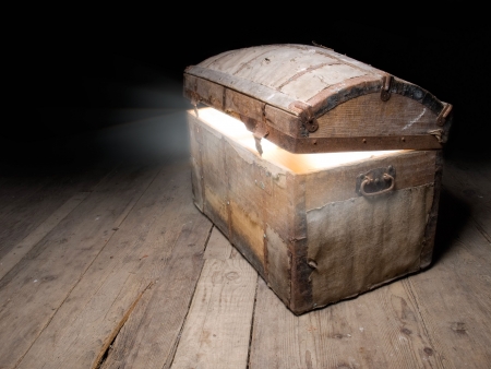 Old wooden treasure chest with strong glow from inside.の写真素材
