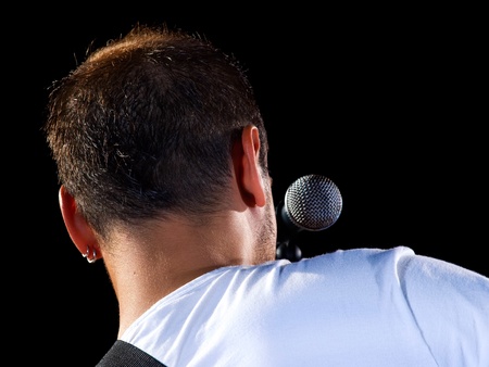 Young musician with his microphone on a dark background.