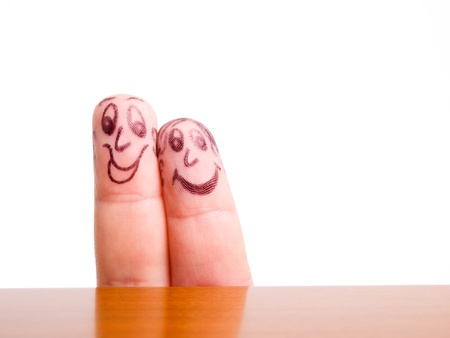 Faces drawn on fingers on a white background.の写真素材