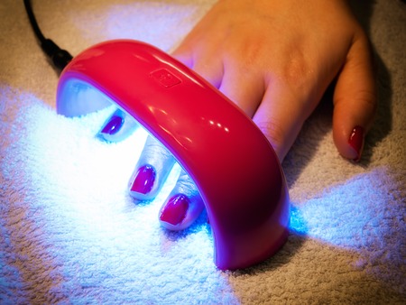 Female hand under UV lamp for drying the gel polishの写真素材