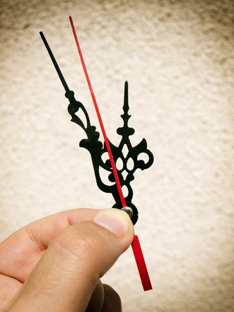 Hand is holding clock hands in position of five minutes to twelve.の写真素材