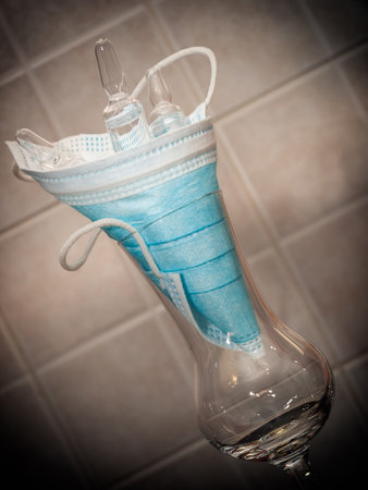 Medical mask and three ampoules in a glass.の写真素材
