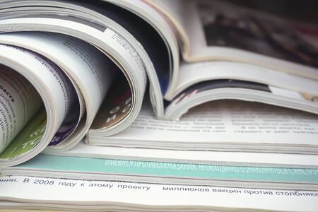 a stack of open glossy magazines lies on the tableの写真素材