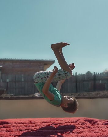 a boy jumps on a trampoline . jumping on an air mattressの写真素材