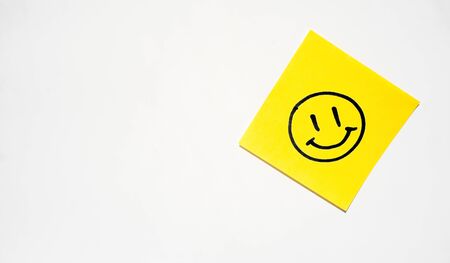 a yellow sticker with a smiley face is on a white backgroundの写真素材