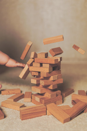 The child's hands pushed the brick and destroyed the tower. Janga wooden box. An imbalance. destruction of blocks. Mistake. Entertainment activities. A game of physical and mental skill.の写真素材