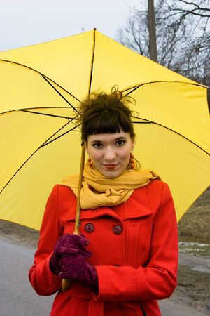  beautiful girl on red coat with yellow  umbrella  の写真素材