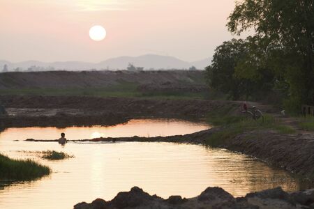 Summer Sunset on river with kids swimming in Vietnamの写真素材