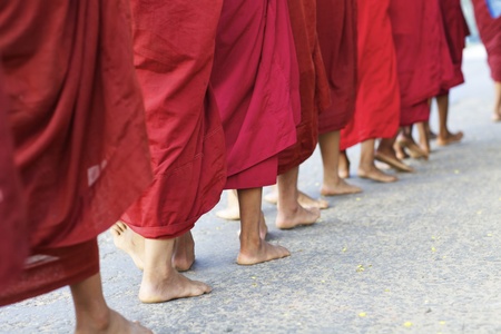 A procession of monks walking barefoot for morning alms in Bagan, Myanmar のeditorial素材