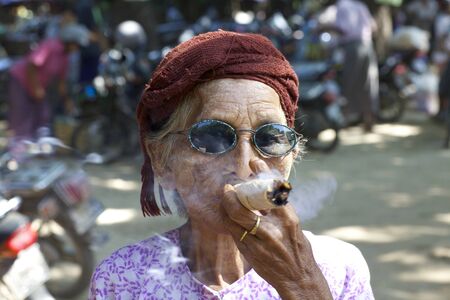 Nyaung-U, Myanmar - October 14, 2011: An unidentified woman smoking a cheroot cigar in Nyaung-U, Myanmar on October 14, 2011. のeditorial素材