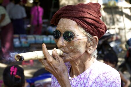 Nyaung-U, Myanmar - October 14, 2011: An unidentified woman smoking a cheroot cigar in Nyaung-U, Myanmar on October 14, 2011のeditorial素材