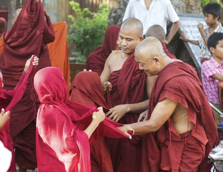 Bagan, Myanmar - Oct. 14: Two adult monks help young novice monks put on their traditional red robes in Bagan, Myanmar on October 14, 2011.のeditorial素材