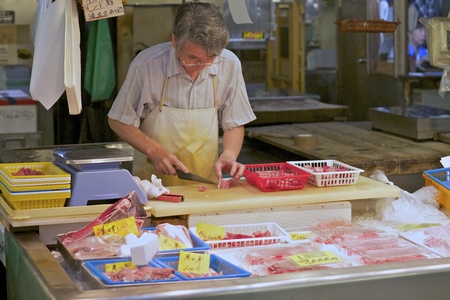 TOKYO - JULY 4: Seafood butcher at the Tsukiji Wholesale Seafood and Fish Market in Tokyo Japan on July 4, 2011. Tsukiji Market is the biggest wholesale fish and seafood market in the world.のeditorial素材