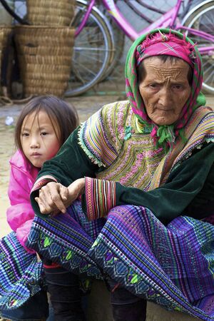 BAC HA, VIETNAM - NOV 21: Unidentified older woman with young girl from the Flower Hmong Ethnic...