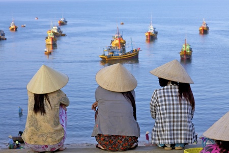  MUI NE, VIETNAM - APRIL 16: Unidentified women await returning fishing boats in Mui Ne, Vietnam at sunrise on April 16, 2011のeditorial素材