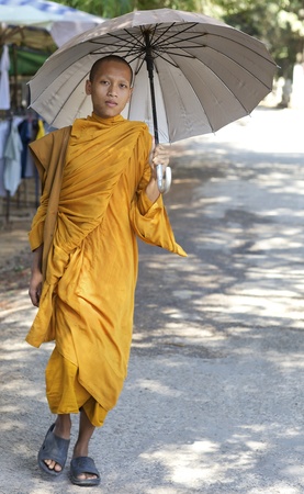 Siem Reap, Cambodia - Jan 25: A monk walking with sun umbrella in Siem Reap, Cambodia on January 25, 2012. のeditorial素材