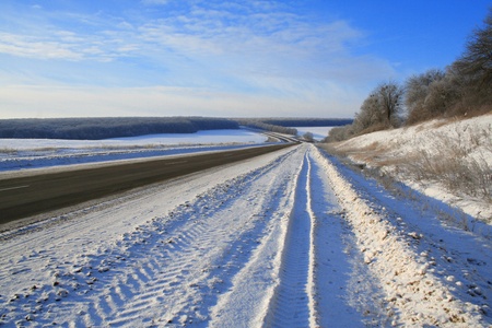 Sunny winter suburban road covered with white snow under a blue sky の写真素材