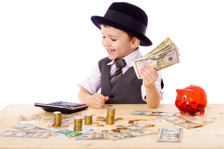 Little boy in black hat and tie at the table counts money, isolated on whiteの写真素材