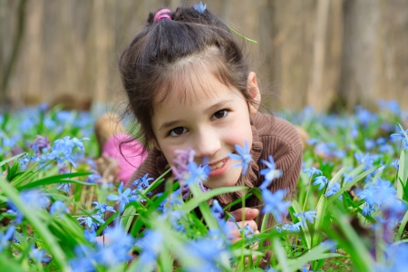 Smiling girl among the bluebells in the forest, blue spring flowers aroundの写真素材