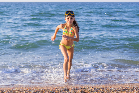Happy little girl runs from the seaの写真素材