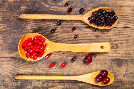 viburnum, black currant and cherry on wooden spoons on rustic backgroundの写真素材