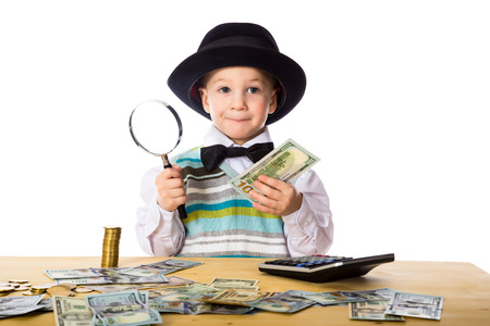 Little boy in black hat counting money on the table, isolated on whiteの写真素材