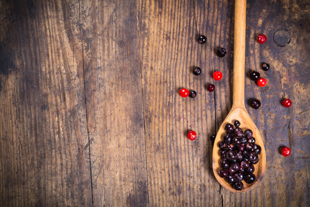 black currant in spoon and viburnum on wooden background with empty copy spaceの写真素材