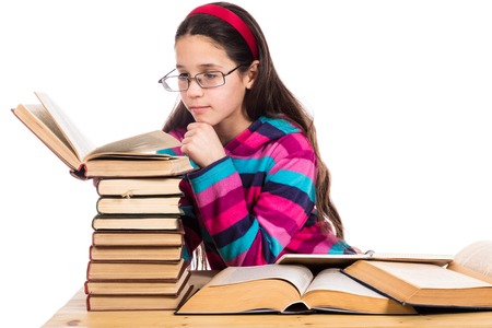 Girl in glasses reading the old book with pile of books, isolated on white