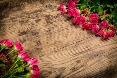Bunch of pink roses on brown wood background with empty space for textの写真素材