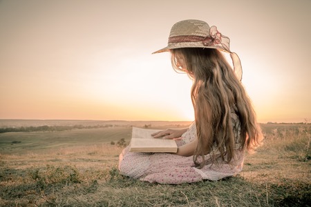 Girl reading the book on rural landscape, sepia toned imageの写真素材