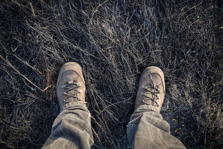 Legs in boots standing on burnt withered grass, outdoorsの写真素材