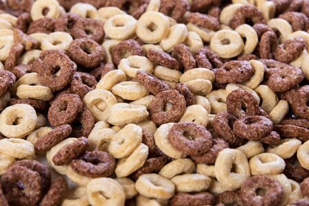 Background texture with mix of white and chocolate corn flakes rings, closeup