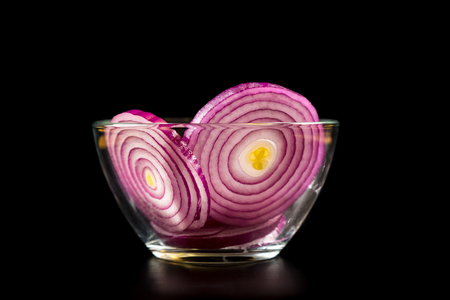Red onion slices in glass bowl on black backgroundの写真素材