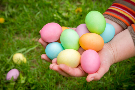 colorful easter eggs in hands on green lawnの写真素材