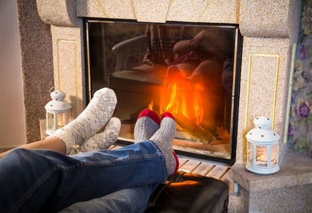 Legs in woolen socks heat up near fireplace, side viewの写真素材