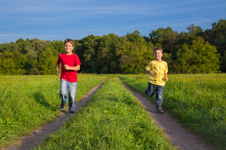Two boys running together on rural roadの写真素材