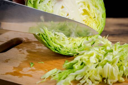 Slicing cabbage on wooden cutting boardの写真素材
