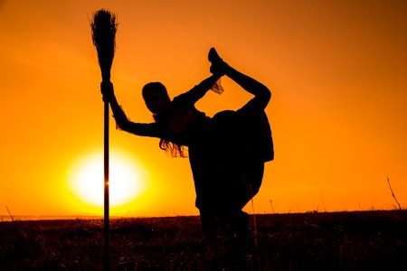 Silhouette of young witch dancing on the broomstickの写真素材