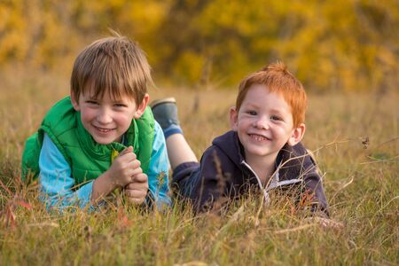two kids lying down on autumn landscape